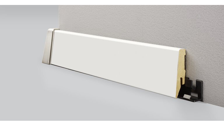 Weiße Sockelleiste mit Klicksystem vor grauer Wand.